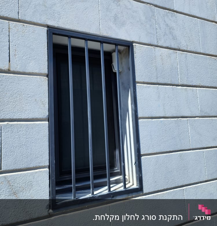 חלון עם סורגים על קיר בטון אפור